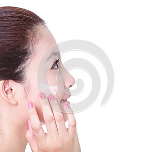 Woman applying moisturizer cream in profile