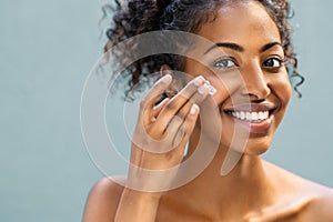 Woman applying moisturizer on face photo