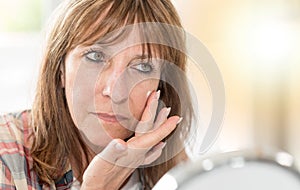 Woman applying moisturizer on her face, light effect