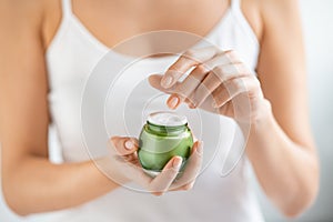 Woman applying moisturizer from jar