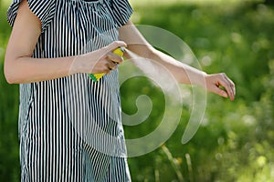 Woman applying mosquito repellent on the hand skin in the forest