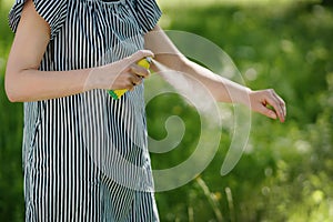Woman applying mosquito repellent on the hand skin in the forest photo