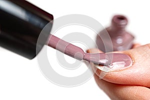 Woman applying nail polish. Beautiful nails. Woman applying polish on nails at home. Pastel nail polish on fingernail. Beauty