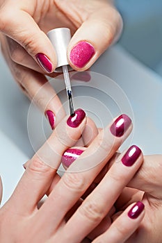 Woman applying nail varnish to finger nails