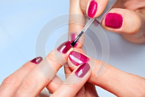 Woman applying nail varnish to finger nails photo