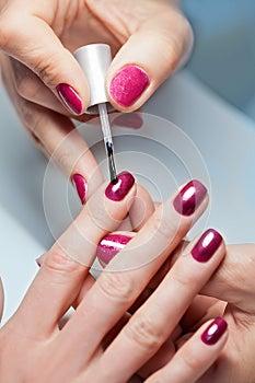 Woman applying nail varnish to finger nails photo