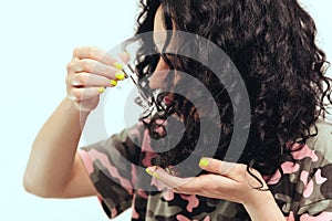 Woman applying natural oil on the tips of her curly hair, close up. Oil hair treatment for woman