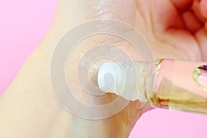 Woman applying natural rollerball oil perfume on her wrist close up