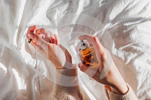 Woman applying perfume on her hand in morning light