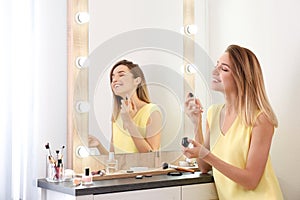 Woman applying perfume near mirror