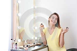 Woman applying perfume near mirror in room