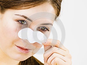 Woman applying pore strips on nose