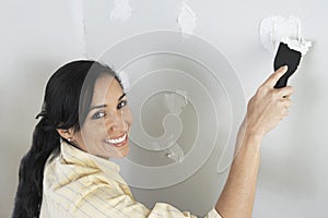 Woman Applying Putty On Wall