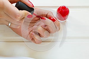 Woman applying red nail polish manicure. Female hand
