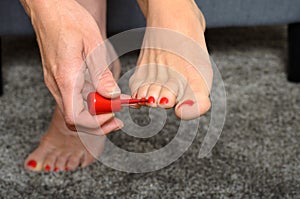 Woman applying red nail varnish