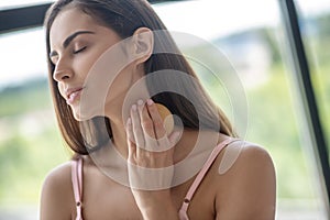 Woman applying scrab to her skin after taking shover