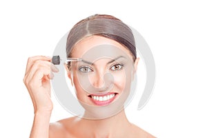 Woman applying serum essence essential oils to her eyebrows