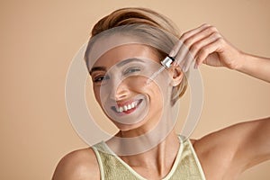 Woman Applying Serum on Face. Woman Applying Essential Oil On Facial Skin