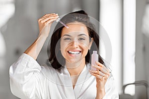 Woman applying serum to forehead in bathroom