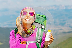 Woman applying sun cream to protect her skin from dangerous uv sun rays high in mountains. Travel healthcare concept