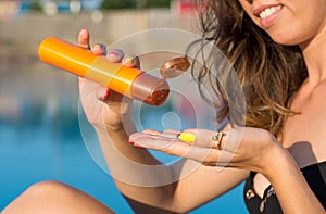 Woman applying sun lotion by the pool