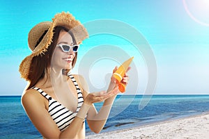 Woman applying sun protection cream at beach, space for text