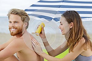 woman applying sunscreen on back man