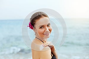 Woman applying sunscreen creme on tanned shoulder. Skincare. Body Sun protection sun cream.