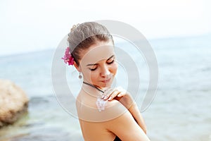 Woman applying sunscreen creme on tanned shoulder. Skincare. Body Sun protection sun cream. Bikini woman smear moisturizing lo