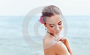 Woman applying sunscreen creme on  tanned  shoulder. Skincare. Body Sun protection sun cream. Bikini  woman smear  moisturizing lo