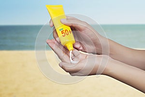 Woman applying sunscreen on her hand with sea background. SPF sunblock protection concept. Travel vacation