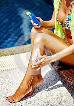 Woman applying sunscreen on legs