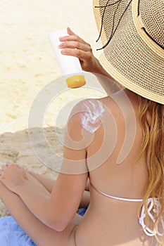 Woman applying sunscreen lotion at the beach