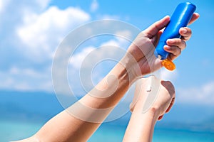 A woman is applying sunscreen and skin care to protect her skin from UV rays. She is applying sunscreen on her hand and arm. The