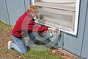 Woman applying window weather stripping in Fall