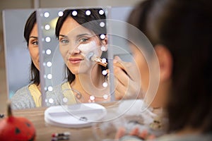 woman applying white face paint looking in mirror