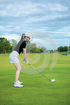 Woman approach to driving golf ball in golf sport club field