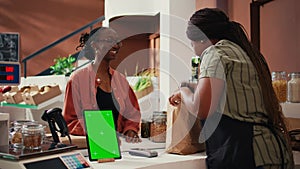 Woman approaching checkout with greenscreen on tablet