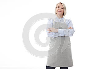 Woman in apron. Confident beautyful woman in apron keeping arms crossed and smiling while standing against white