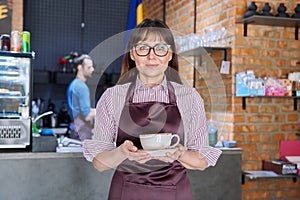 Woman in apron, food service coffee shop worker, small business owner with cup of coffee