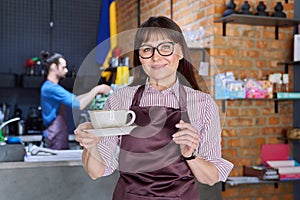 Woman in apron, food service coffee shop worker, small business owner with cup of coffee