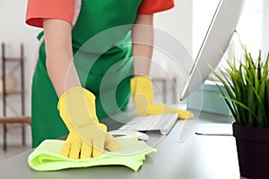 Woman in apron and gloves cleaning office