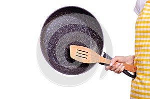 Woman in apron in hand frying pan and kitchen spatula