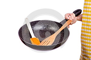 Woman in apron in hand frying pan and kitchen spatula