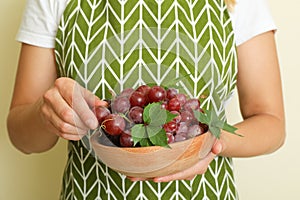 Woman in apron hold bowl with grape
