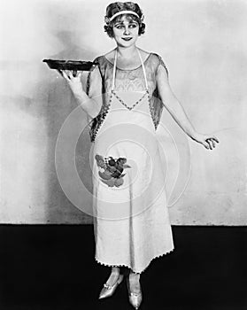 Woman in an apron holding a plate of food and smiling