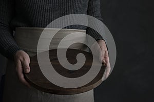 Woman in an apron holding a wooden tray