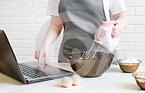 Woman in an apron prepares food and searches for a recipe on the internet. online cooking training