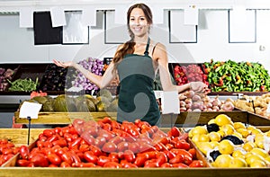 Woman in apron selling organic tomatoes in shop