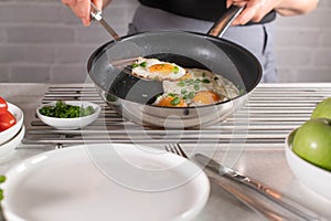 Woman with apron is serving fresh pan fried egg with a spatula on a plate